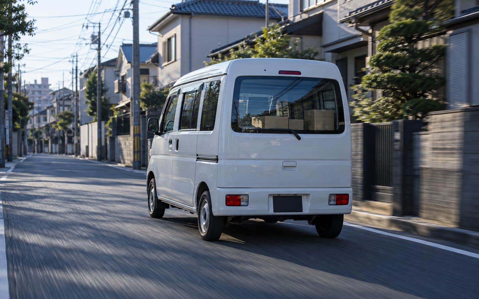 朝の住宅街を走る白い軽バン